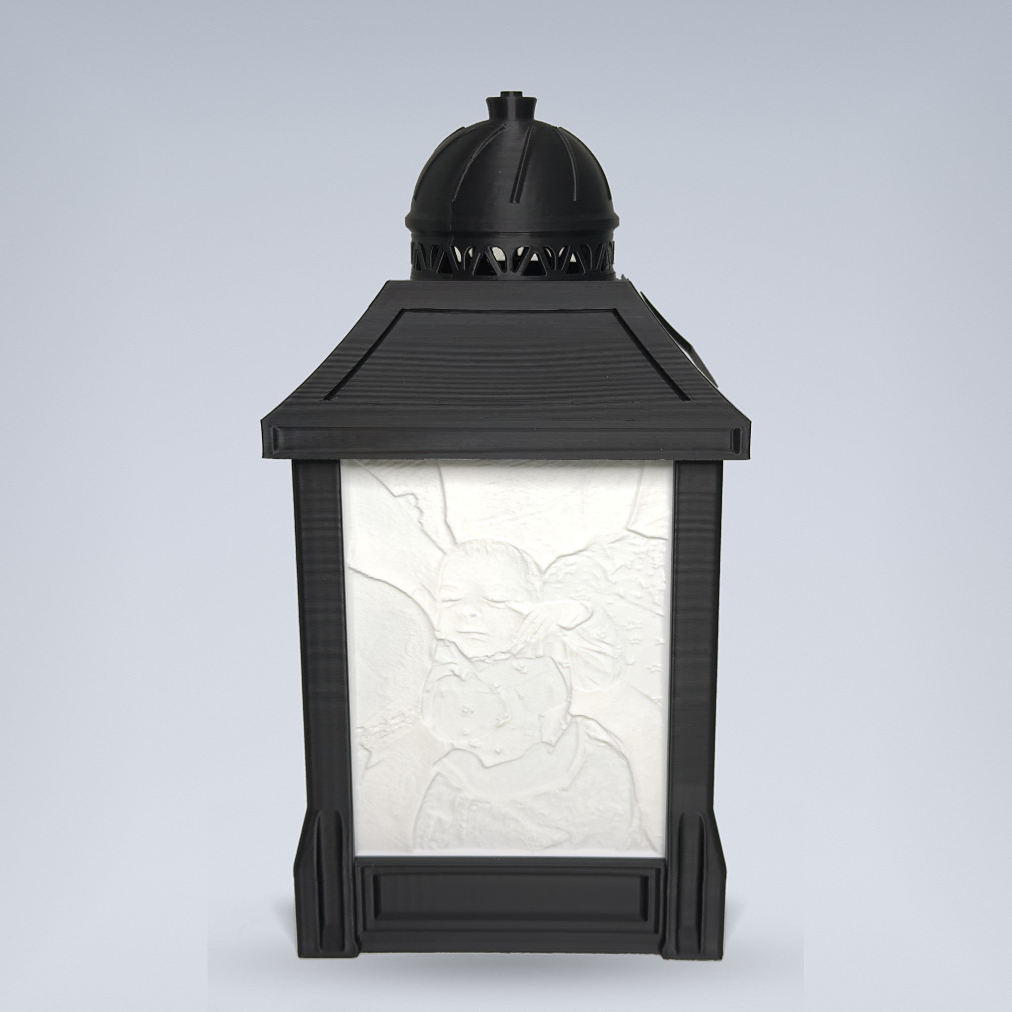 Custom lithophane photo lamp — black 3D printed lantern by day with sculpted photo relief panel, studio background