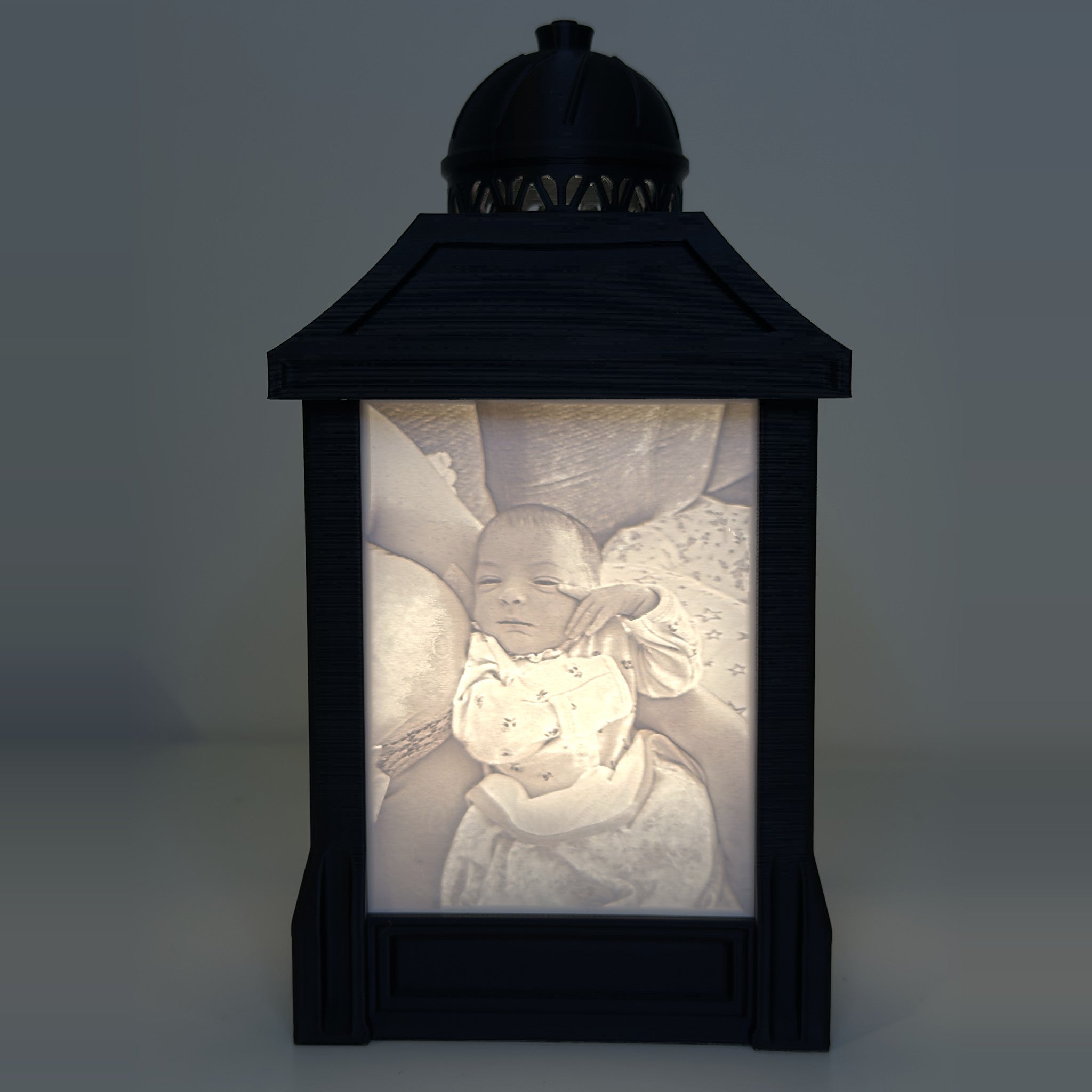 Custom lithophane photo lamp lit at night, revealing a baby photo in glowing sepia detail
